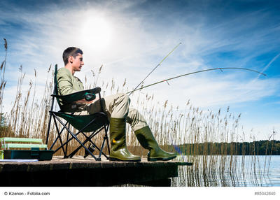 Bild vergrößern: Man fishing at lake sitting on jetty close to the water